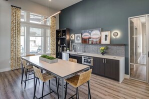 A modern kitchen with a dining area, featuring a large window, dark wall, and contemporary design elements.