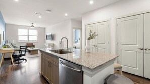 A modern kitchen with a granite countertop, stainless steel appliances, and a dining area with a table and chairs. - Landing | Incredible 2BD, Clubhouse, Pool (Rockwall)