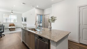 A modern kitchen with granite countertops, stainless steel appliances, and a built-in dishwasher. - Landing | Modern 1BD, Gym, Pool (Rockwall)