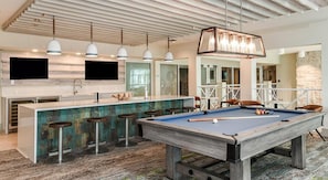 A pool table in a modern kitchen with bar stools, pendant lights, and a stone wall. - Landing | Incredible 2BD, Clubhouse, Gym (Apopka)