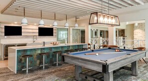 A pool table in a modern kitchen with bar stools, pendant lights, and a stone wall. - Landing | Amazing 2BD, Clubhouse, Gym (Apopka)