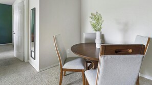 A dining area with a round table, four chairs, a vase with a plant, and a door with a mirror. - Landing | Incredible 2BD in Copperfield (Cypress)