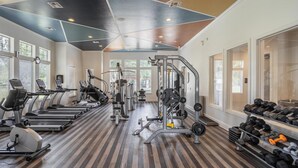 Une salle de sport équipée de tapis de course, de vélos elliptiques, d’appareils de musculation et de poids libres.