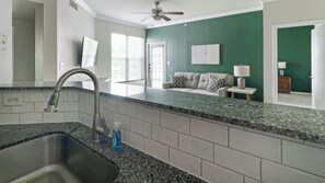 Eine Küche mit Granitarbeitsplatte, Spüle aus Edelstahl und Deckenventilator.