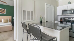 A compact kitchen with a central island, a microwave, and an oven. - Landing | Incredible 1BD in Copperfield (Cypress)