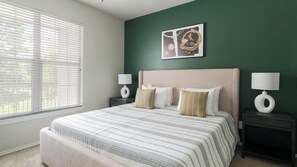 Ein Schlafzimmer mit einem Bett, zwei Nachttischen, einem Fenster mit Jalousien und einem Wandbild.