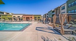 A pool area with lounge chairs and a building with multiple balconies.