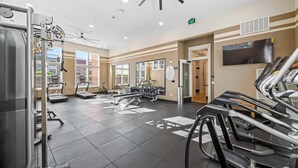 Une salle de sport équipée de tapis de course, d’appareils de musculation et d’un téléviseur fixé au mur.