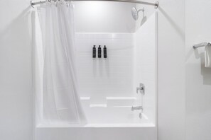 A white bathtub with a showerhead, a curtain, and a set of toiletries on the wall. - Landing | Beautiful 1BD, Clubhouse, Gym (Santa Rosa)