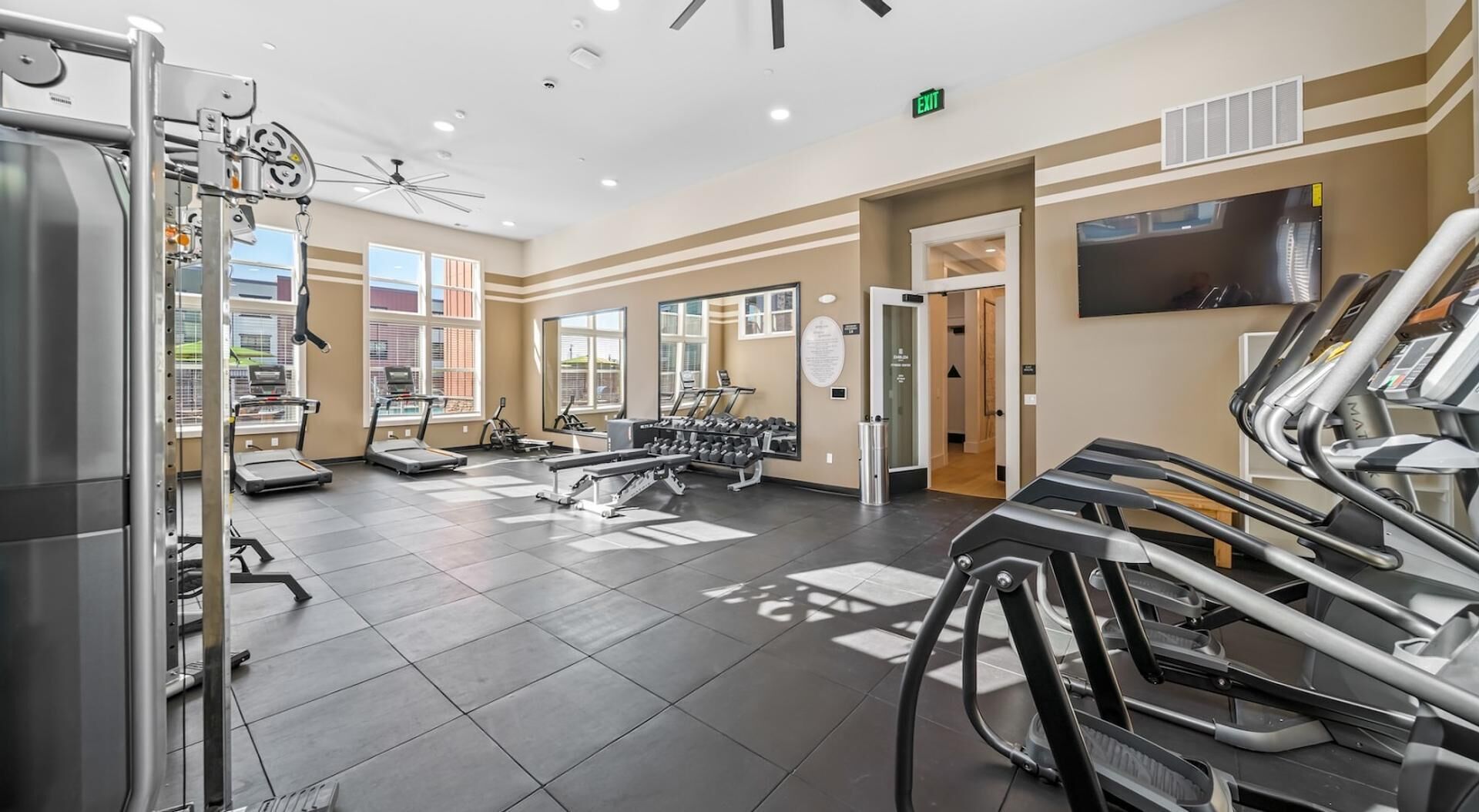 A gym with treadmills, weight machines, and a TV on the wall.