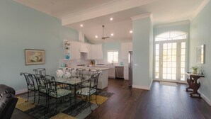 A spacious kitchen with white cabinets, a dining area with a glass table and chairs, and a view of the living area through an open door. - Tranquil 4-bedroom 3-bath house with 50' boat dock in delightful Treasure Cay (Treasure Cay)