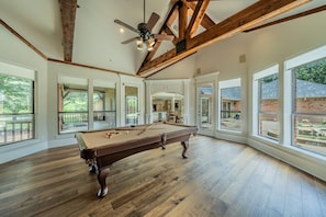 A spacious indoor pool table area with large windows and a high ceiling.