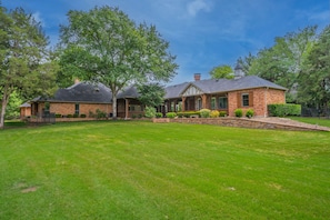 A two-story brick house with a well-maintained lawn and mature trees.