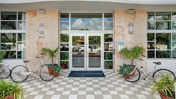 A hotel entrance with a checkered floor, two bicycles parked outside, and potted plants. - Hotel Trouvail | 2 Queen | Art Deco Charm, Beach Days, Euro-Miami Vibe | 2 Units (Miami Beach)