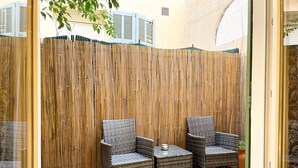 A room with two wicker chairs and a small table, a bamboo screen wall, and a tiled floor. - Viva Riviera Charming Studio with Terrace (Cannes)