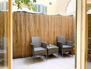 A room with two wicker chairs and a small table, a bamboo screen wall, and a tiled floor. - Viva Riviera Charming Studio with Terrace (Cannes)
