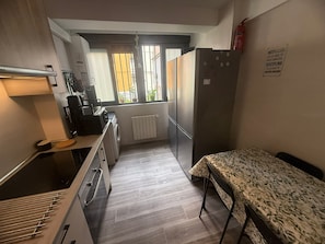 Ett kompakt kök med tvättmaskin, kylskåp och en liten matplats med ett bord.
