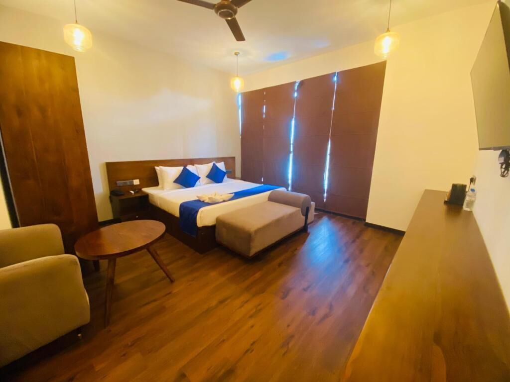 A hotel room with a bed, a small sofa, a round table, and a ceiling fan.