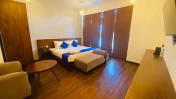 Una habitación de hotel con cama, un pequeño sofá, una mesa redonda y un ventilador de techo.