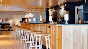 A bar area with wooden stools, a counter, and a hanging light fixture. - Laurel | 2 Queen | Olympic History, Mirror Lake, On-Site Restaurant (Essex County)