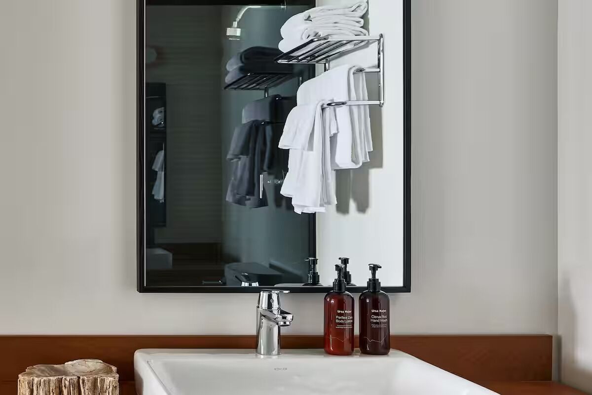 A bathroom with a large mirror, a sink, and a towel rack with folded towels.