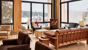 A cozy living room with a fireplace, large windows, and wooden furniture. - King Jr | Laurel | Mirror Lake, Olympic History, Adirondack Adventures (Essex County)