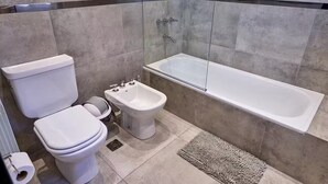 Un baño con inodoro, bidé y bañera.