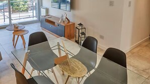 Un comedor moderno con una mesa de vidrio, sillas negras y un aplique de techo de madera.