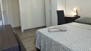 A bedroom with a bed, a desk, a chair, a nightstand, and a door. - Room-cozy Guest Room in Modern Madrid Fl (Madrid)