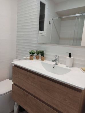 A bathroom with a white sink, wooden vanity, and a mirror above.