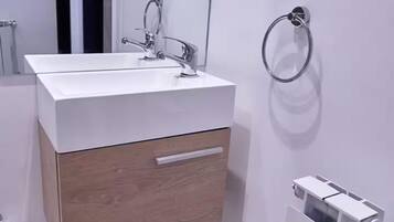 A modern bathroom with a white sink, wooden cabinet, and a towel ring.