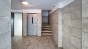 A hallway with a door, a staircase, and tiled walls. - Hayarkon Joie - Two Bedroom Apartment, Sleeps 4 (Tel Aviv-Yafo)