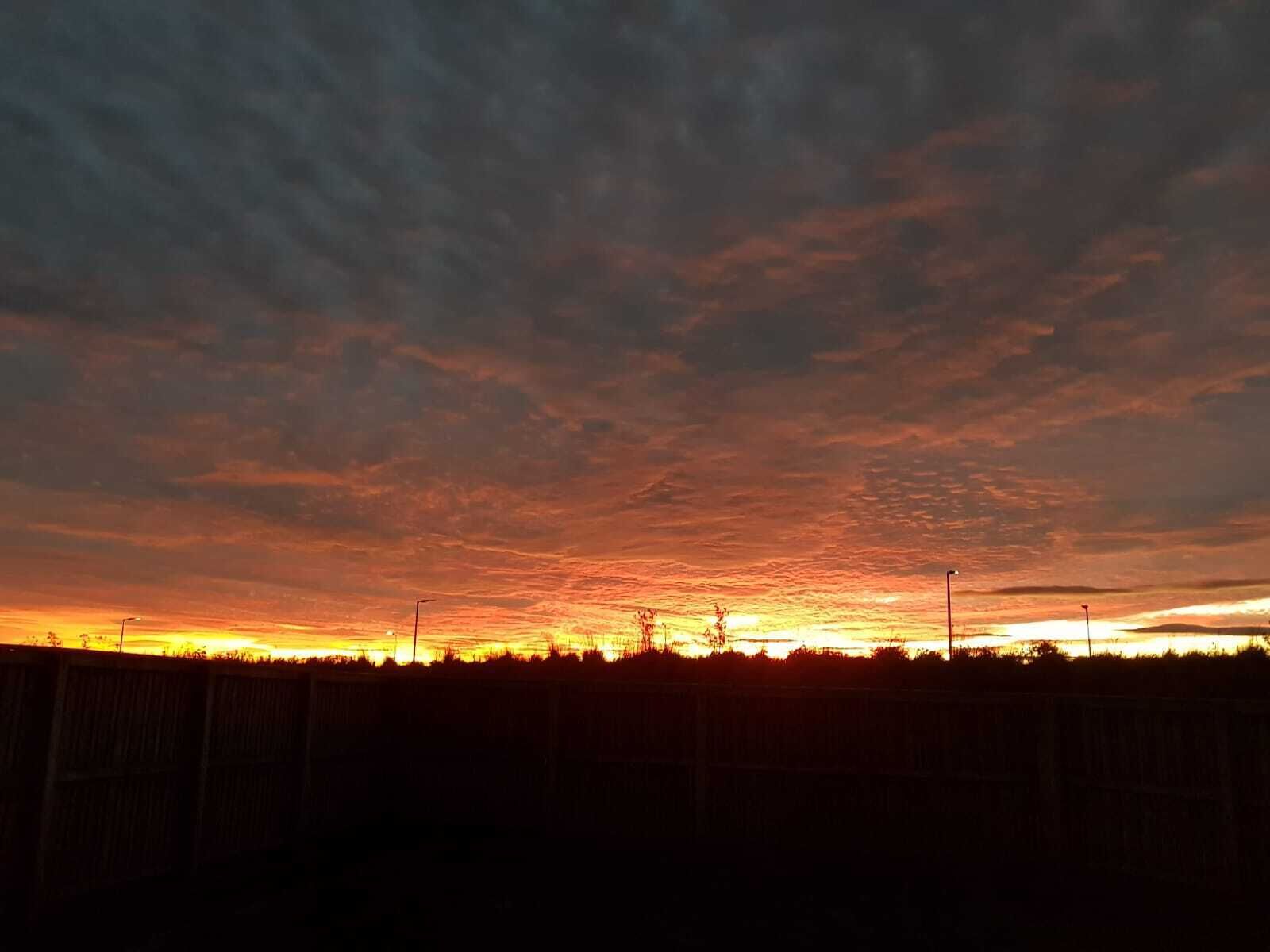 Un atardecer sobre un paisaje llano con una cerca al frente.