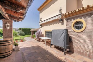 Un pati amb taula i cadires, una barbacoa coberta i un dimoni.
