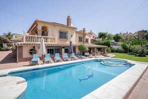 Ein Wohnhaus mit Swimmingpool, Liegestühlen und Garten.