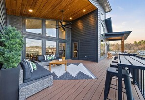 Ein modernes Haus mit Terrasse, Sitzgelegenheiten im Freien und großen Fenstern.