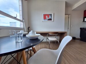 Un'area pranzo con un tavolo rotondo, sedie bianche e un quadro appeso al muro.