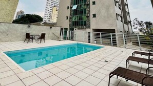 Un edificio de gran altura con piscina y asientos al aire libre.