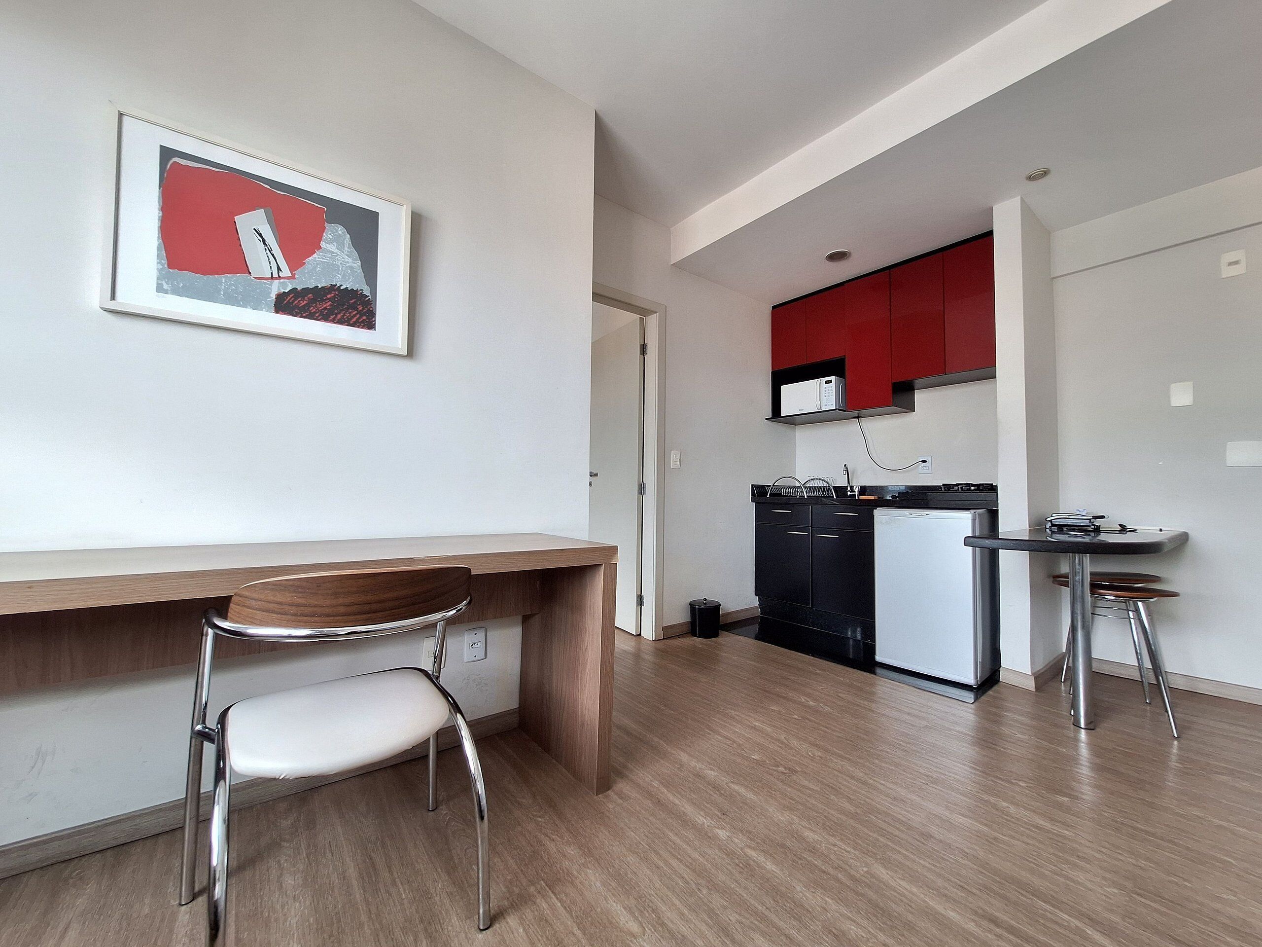 A modern kitchen with a microwave, refrigerator, and a small dining area with a chair and table.