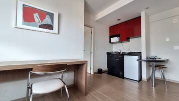 A modern kitchen with a microwave, refrigerator, and a small dining area with a chair and table.