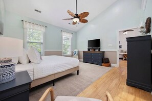 Ein Schlafzimmer mit einem Bett, einem Deckenventilator, einer Kommode, einem Fernseher und einem Schrank.