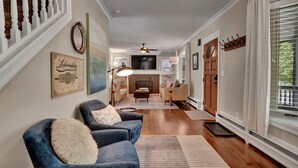 A living room with a fireplace, a television, and a staircase. - Central Royal Oak 3BR Home Near Woodward, Birmingham & Detroit Zoo (Royal Oak)