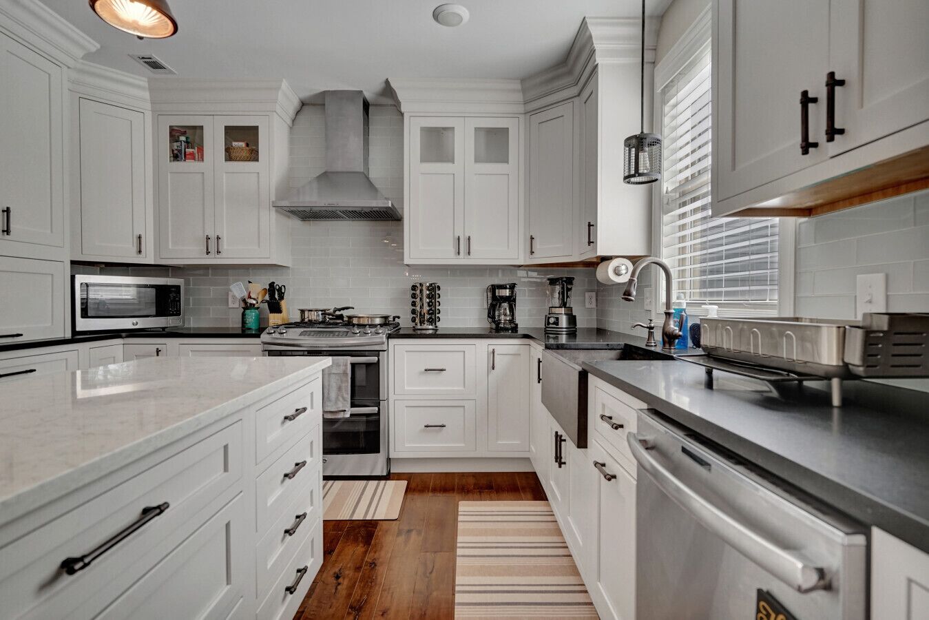A modern kitchen with white cabinetry, a stainless steel range, and a built-in oven.