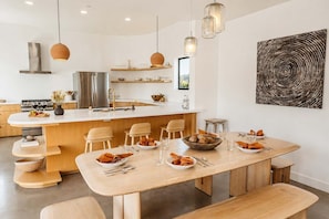 Una cocina moderna con una isla central, sillas de madera y una mesa de comedor preparada para dos.