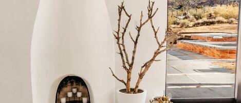 A modern interior with a fireplace, a potted plant, and a view of a mountainous landscape.