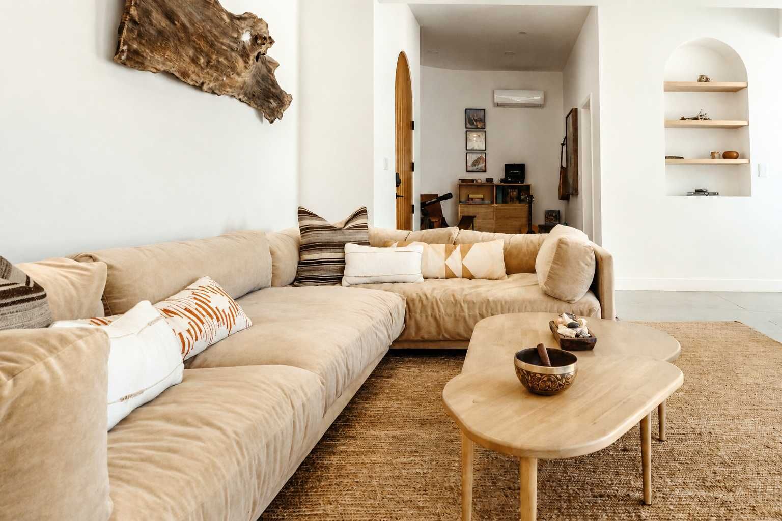 Un salon avec un canapé beige, une table basse en bois et une décoration murale de style rustique.