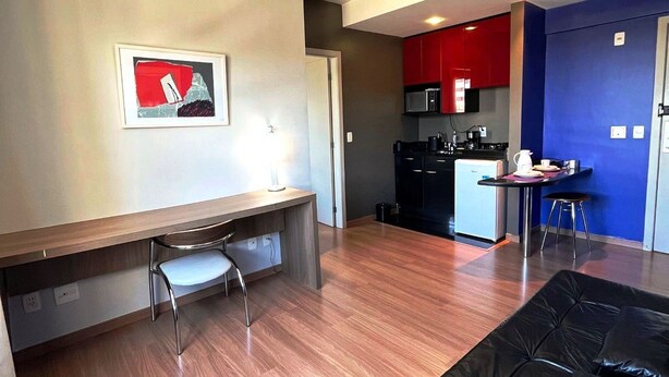 A modern apartment with a dining area, kitchenette, and a black leather sofa. - LK Barro Preto 5 (Belo Horizonte)