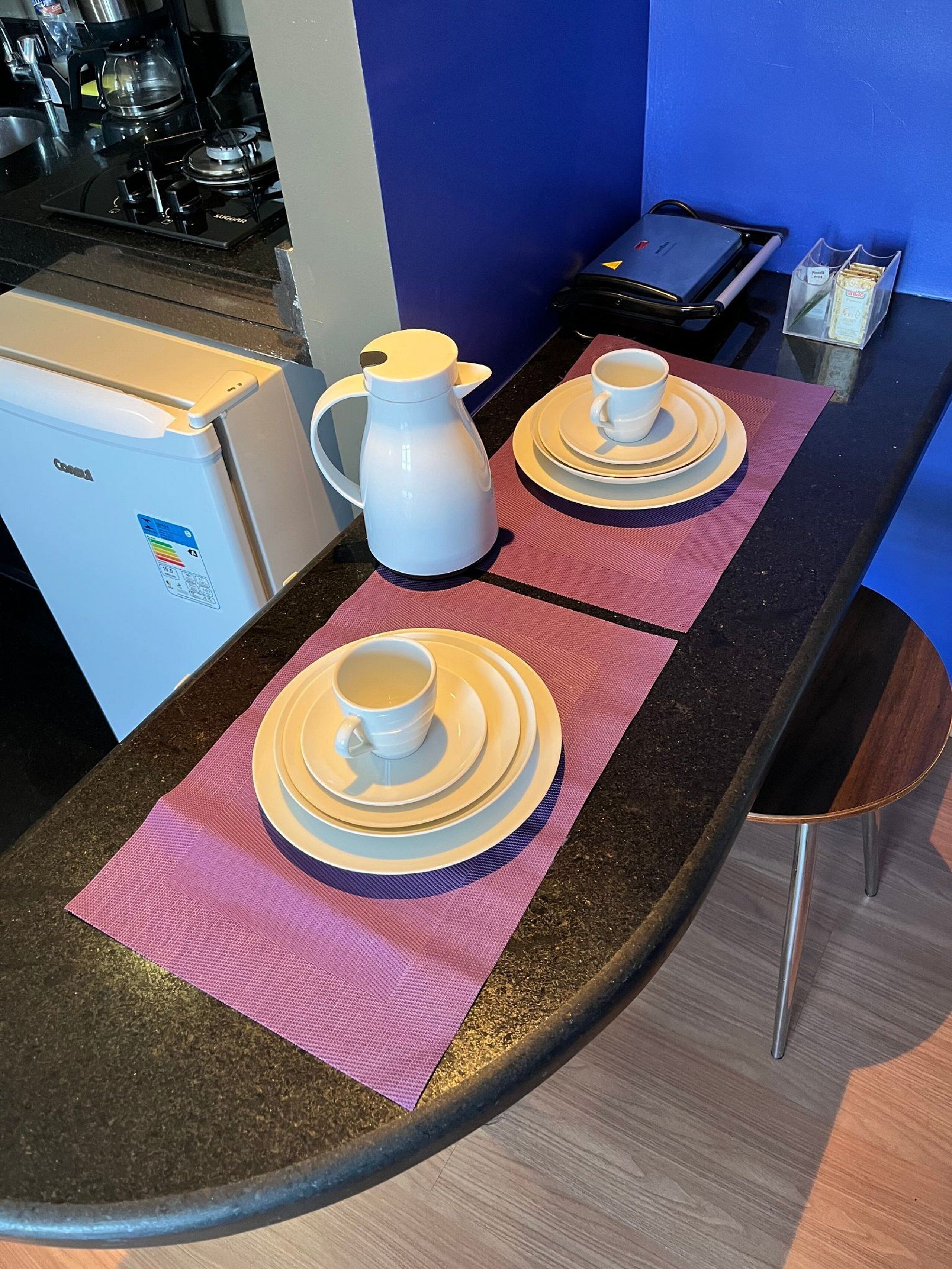 A kitchenette with a coffee maker, a kettle, and a small refrigerator.