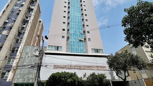 A tall building with a blue glass facade, surrounded by other buildings and a clear sky. - LK Barro Preto 5 (Belo Horizonte)