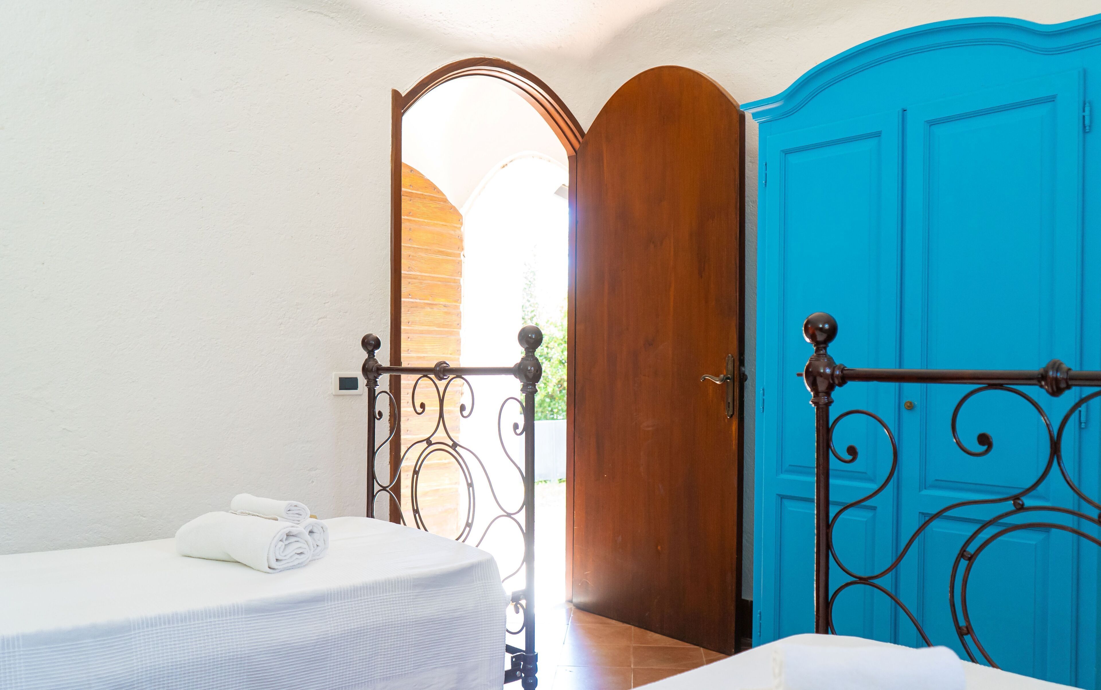 A bedroom with a bed, a wooden door, and a blue door.